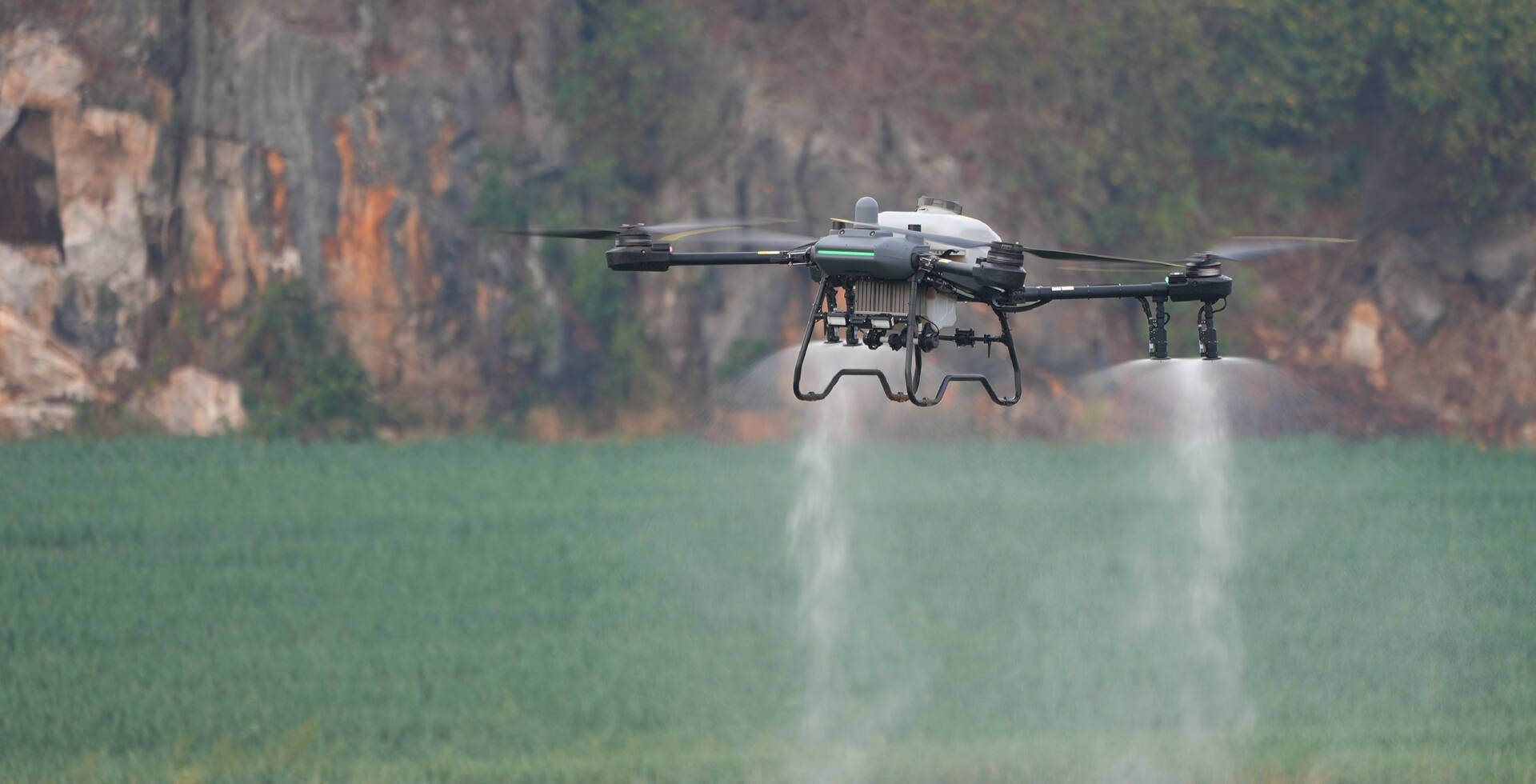 Q100P drone spraying a green field